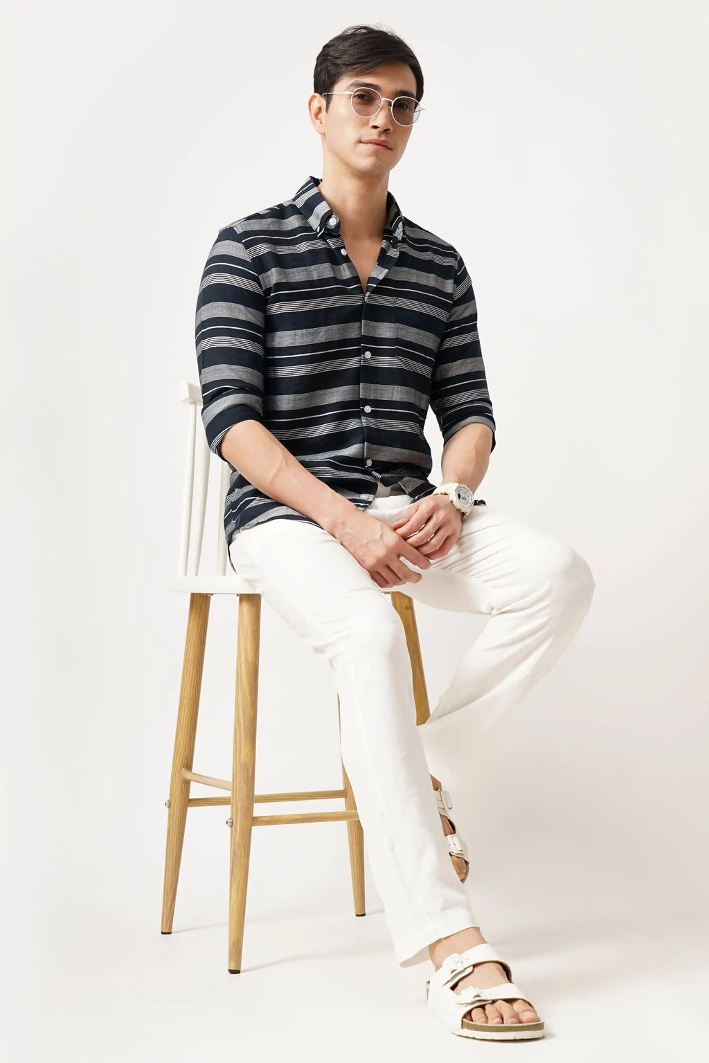 NOIELINE STRIPED SHIRT worn by a man, featuring black and grey stripes, paired with white trousers for a sophisticated look.