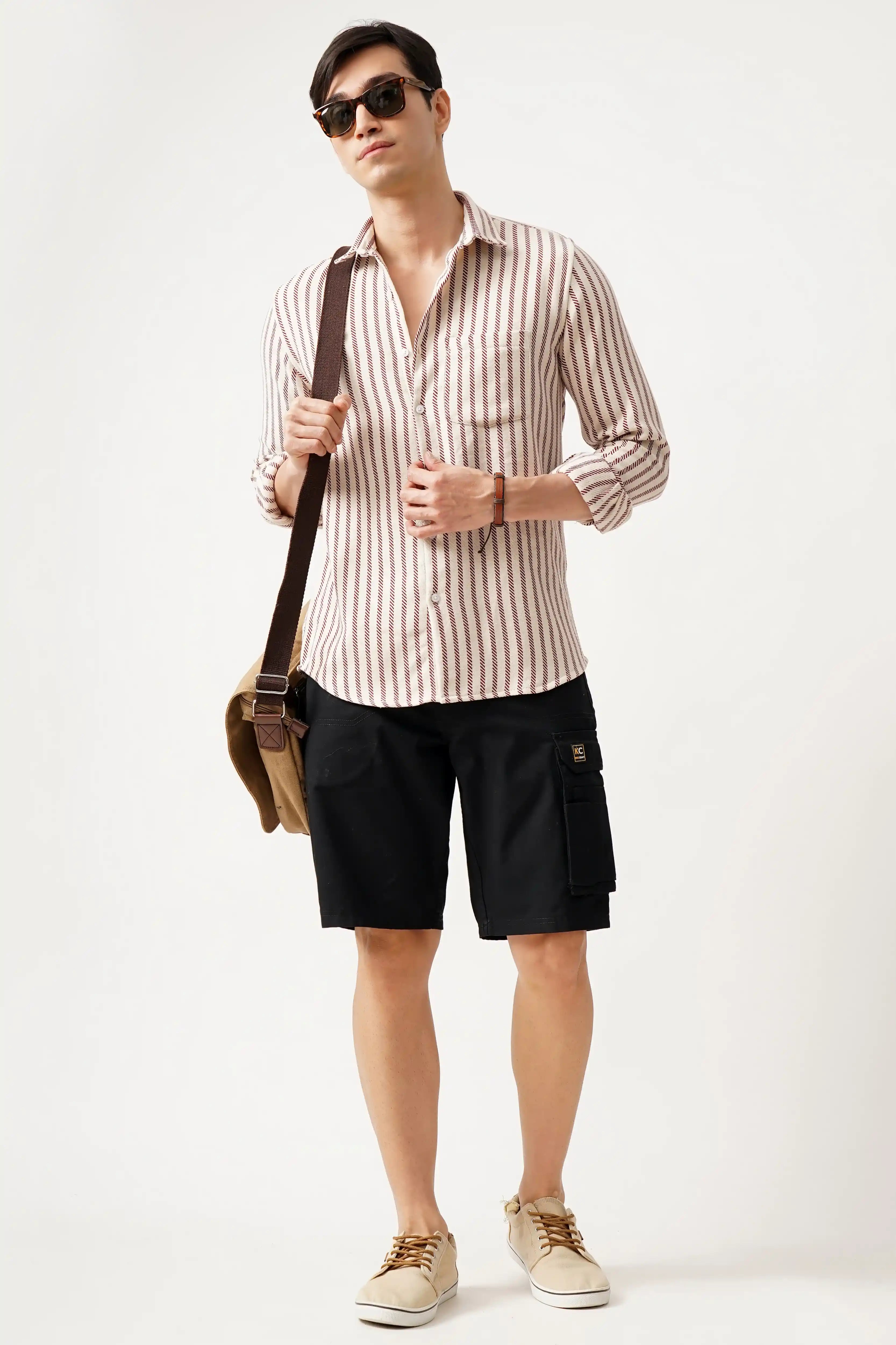 Man wearing Striluxe striped shirt with shorts, carrying a shoulder bag.