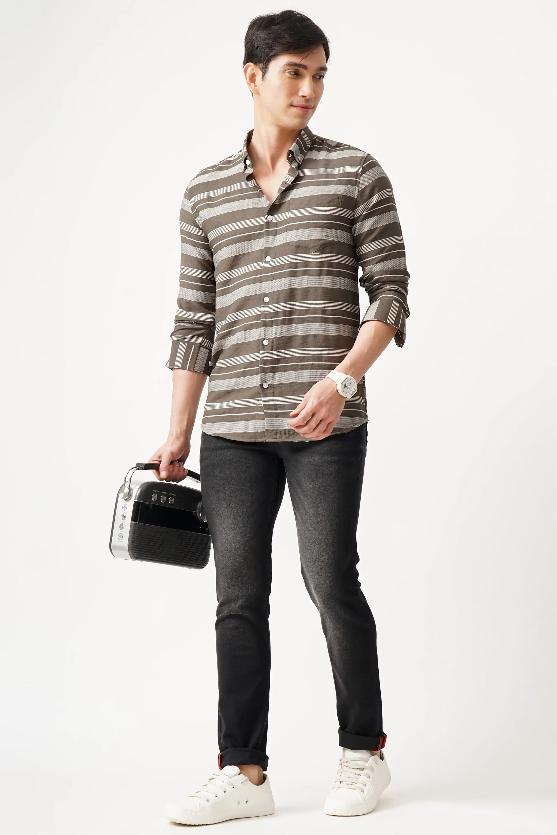 Modern man wearing Ecliptio Striped Shirt with sleek striped pattern, paired with jeans and white sneakers.