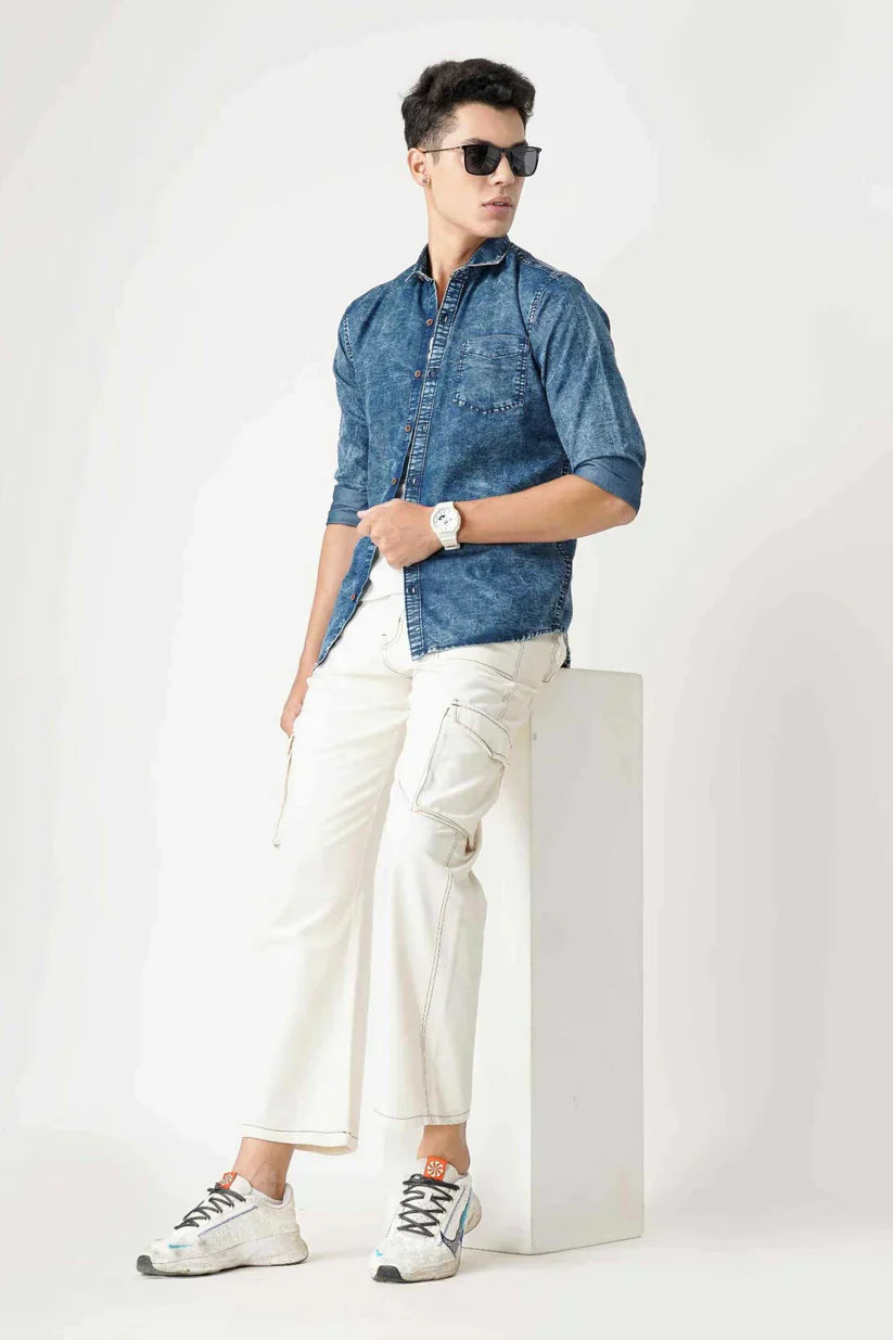 Man wearing stylish blue denim shirt with white pants and sunglasses.