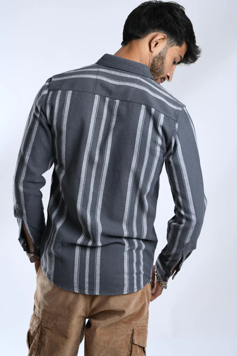 Man wearing a grey white striped shirt made from mock linen cotton fabric.