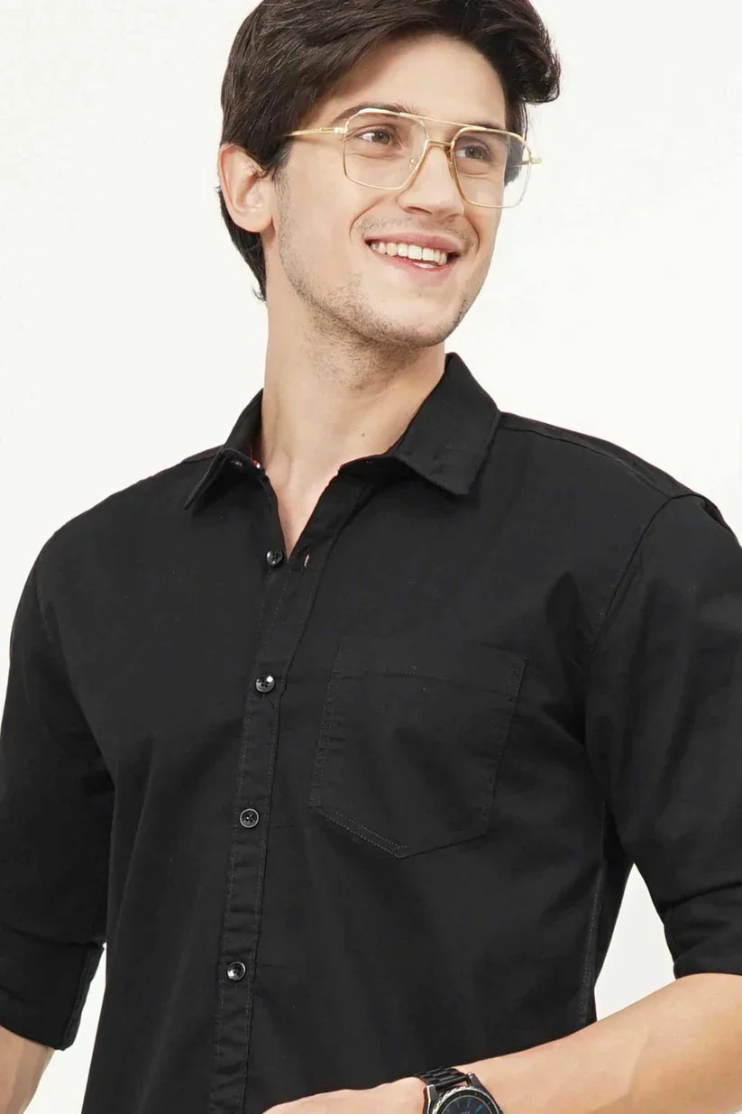 Man wearing a classic black plain shirt made from 100% cotton fabric.