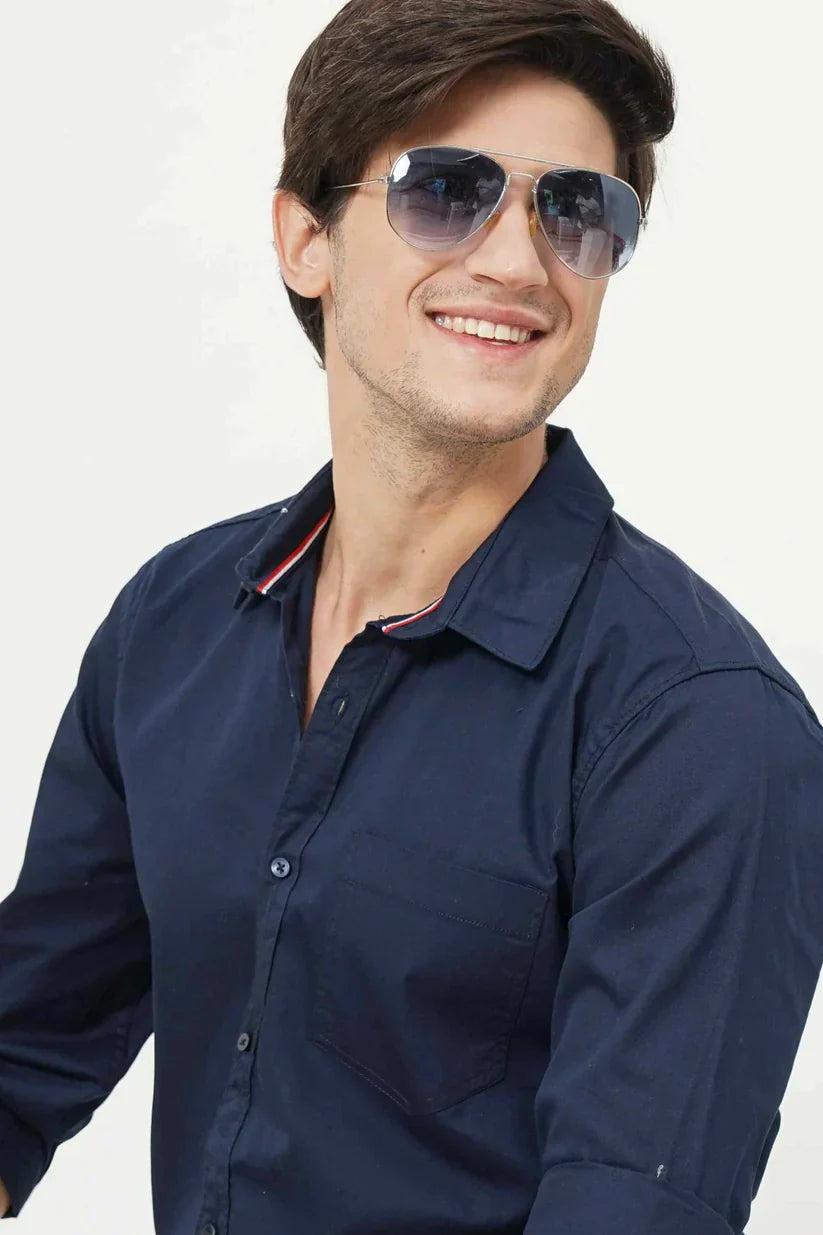 Man wearing a blueish plain shirt made of cotton fabric.