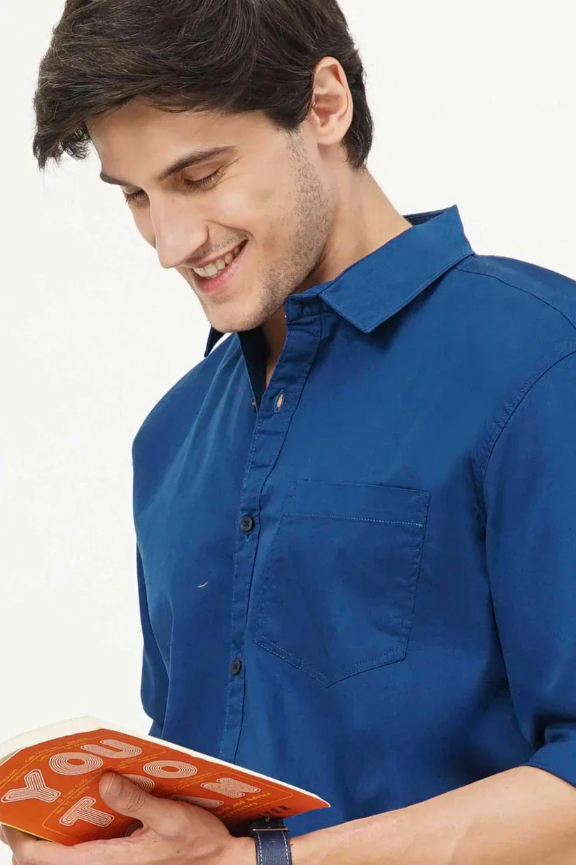 Man wearing a stylish blue plain shirt made of 100% cotton fabric.